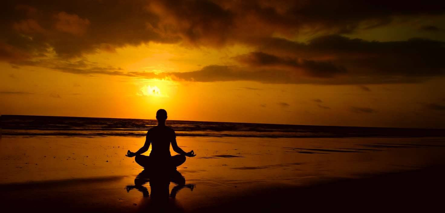 Sunrise over calm ocean with meditating silhouette